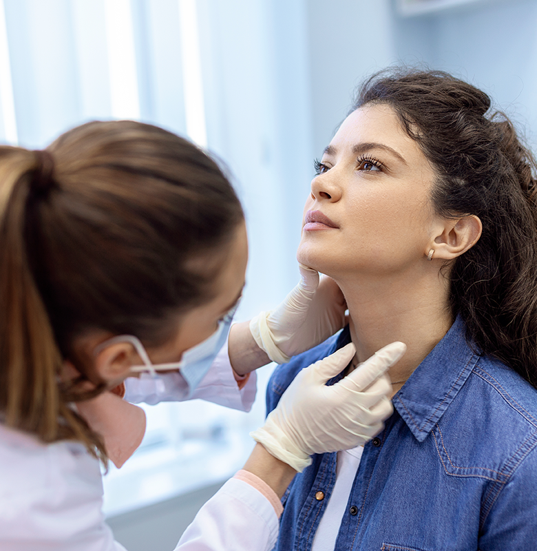 A woman looks up while a physician examines her throat.