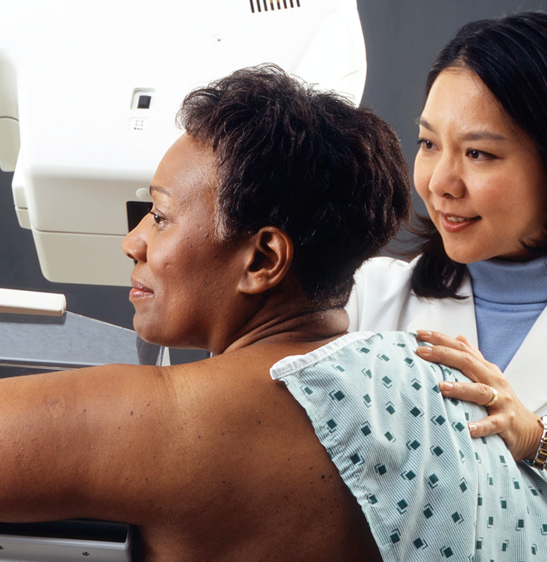 A woman receives a mammogram from a physician.