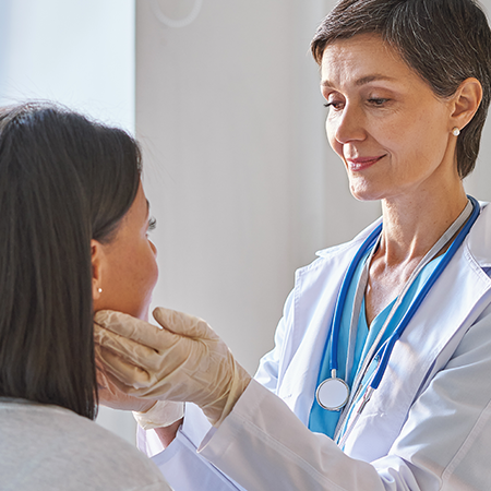 A physician gently feels a patient’s neck to check the thyroid.