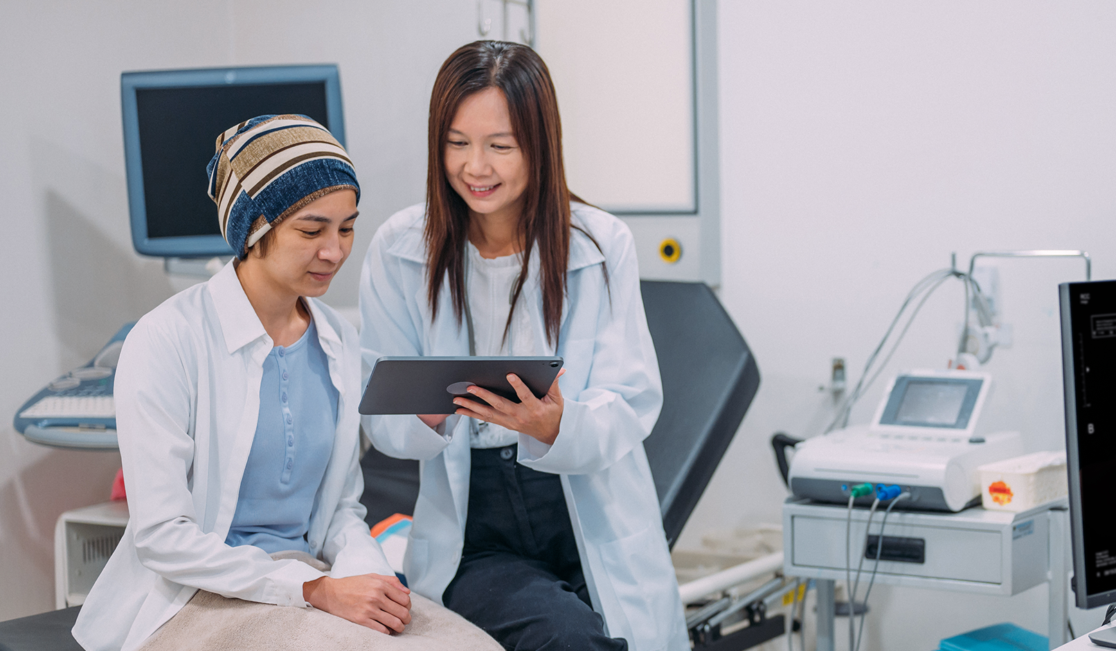 A smiling physician shows medical information to a patient.