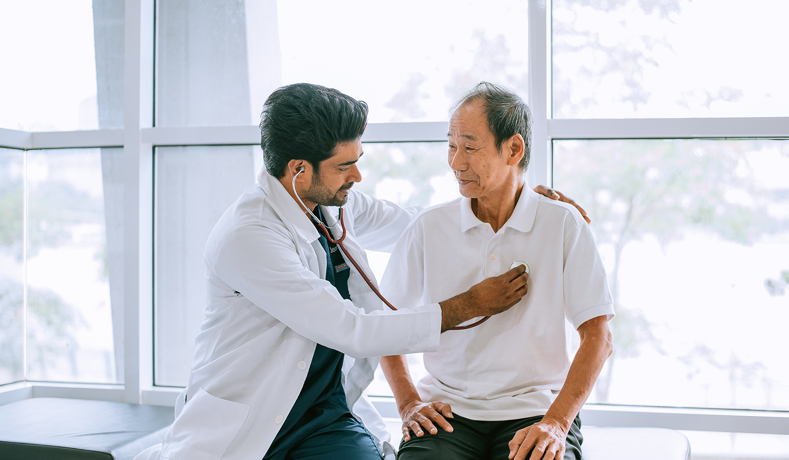 A physician listens to a patient’s chest with a stethoscope.