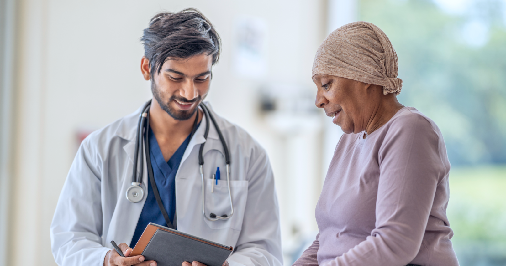 A physician and a patient smile while reviewing information together.