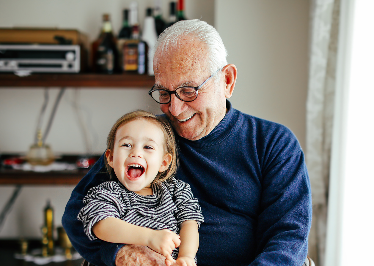 An older man holding a smiling baby.