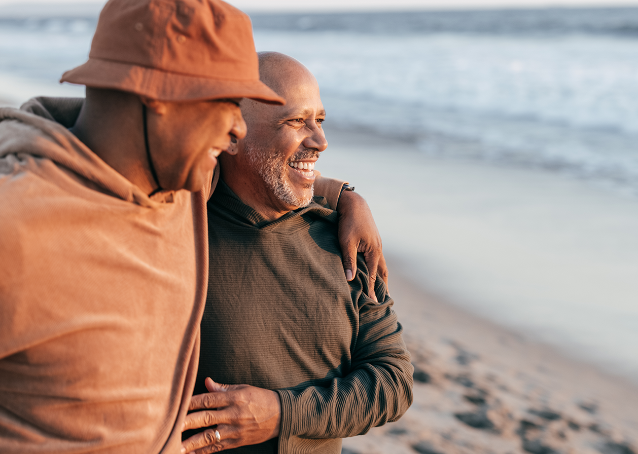 Two men laugh together at the beach.