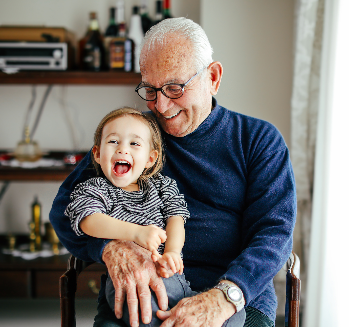 An older man holding a smiling baby.