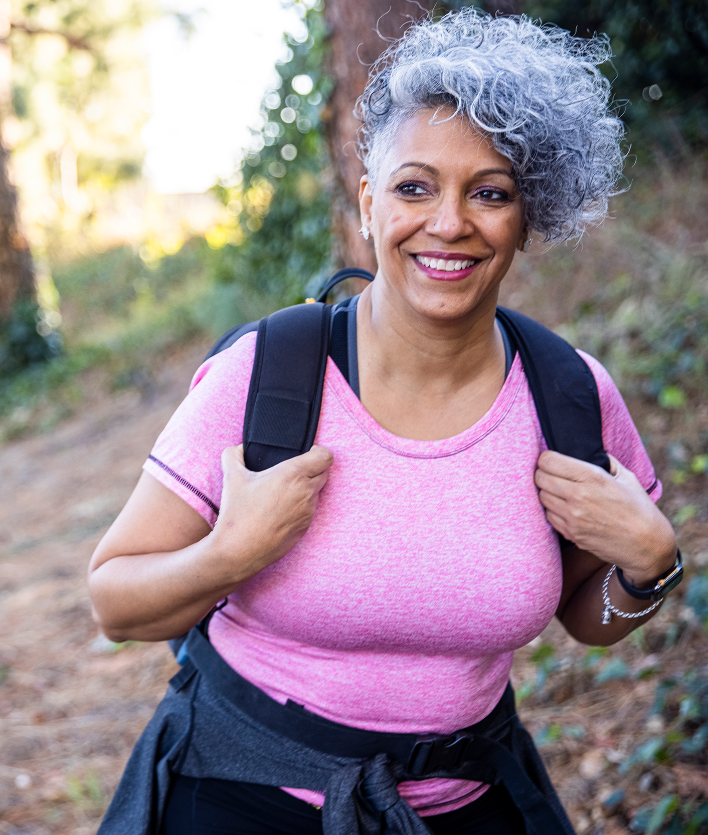 A smiling older woman goes on a hike.