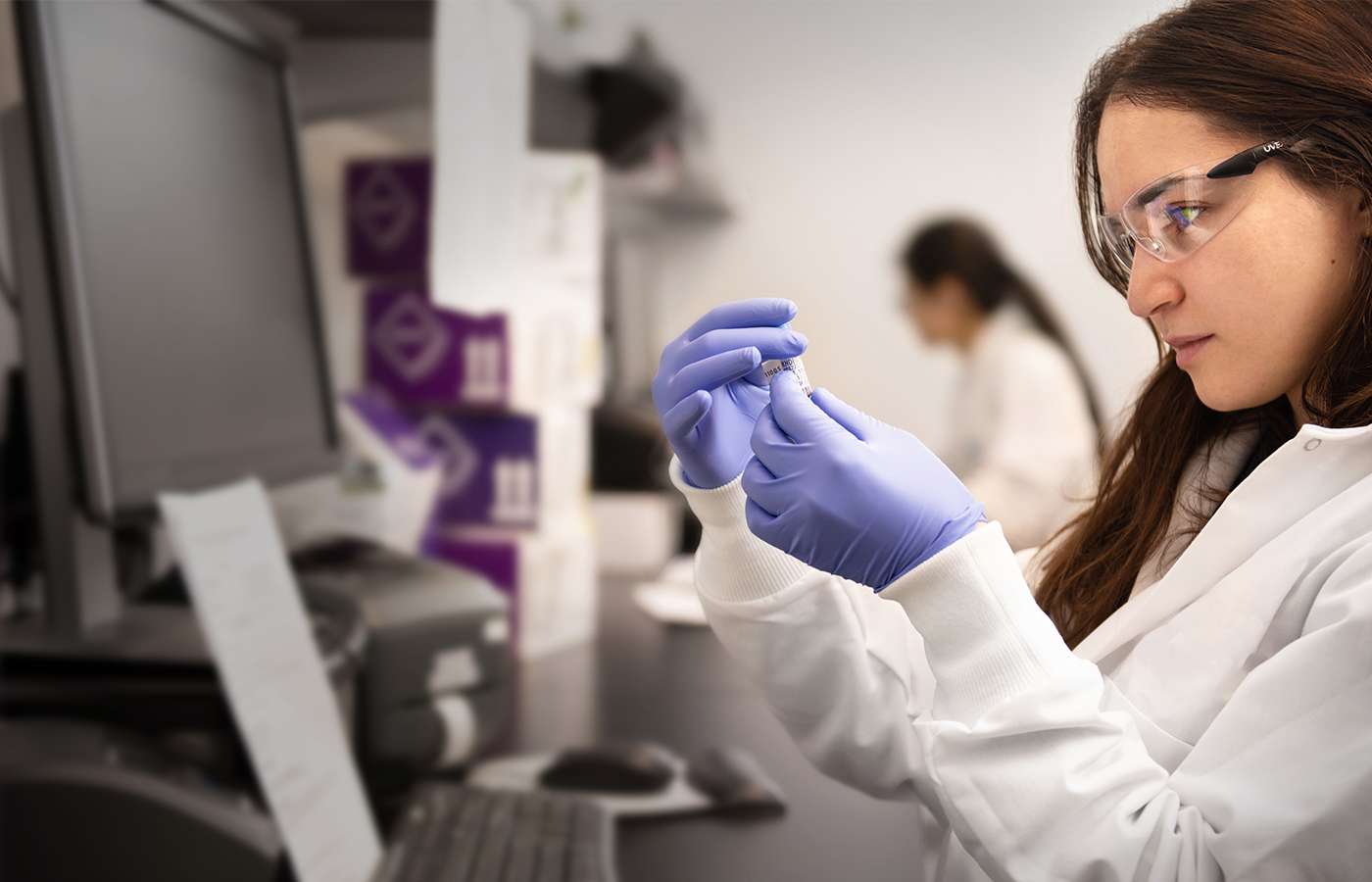 A lab worker examines a label on a vial.