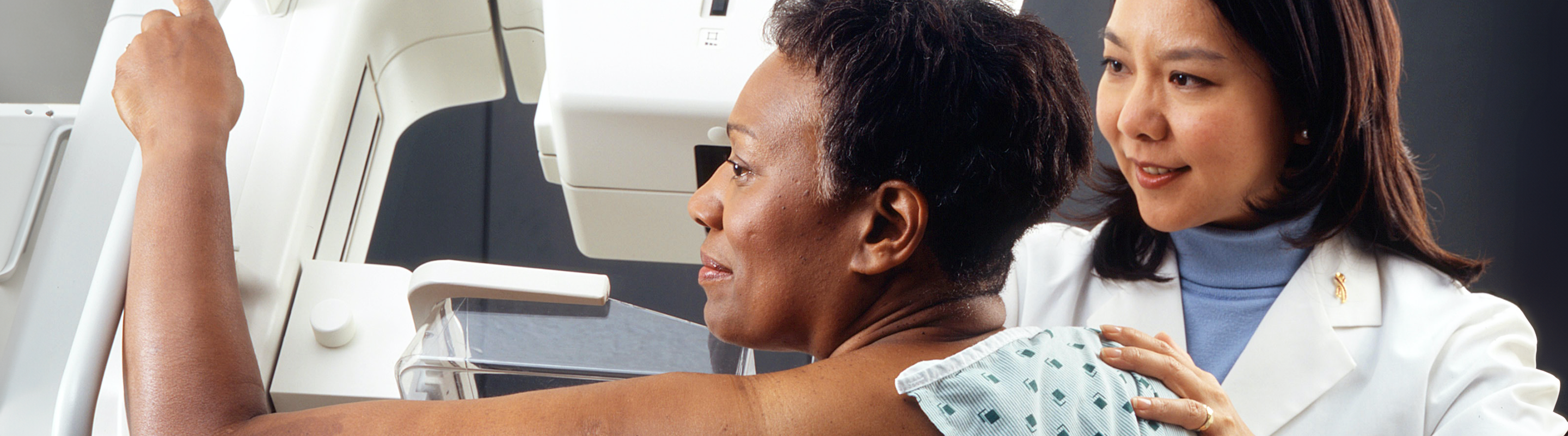 A woman receives a mammogram from a physician.