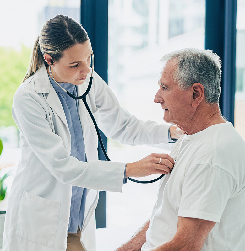 A physician listens to an older patient’s chest with a stethoscope.