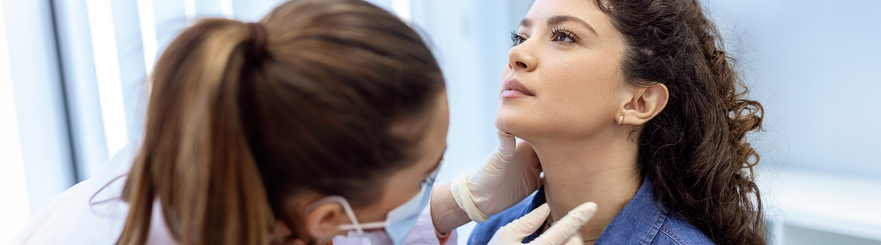 A woman looks up while a physician examines her throat.