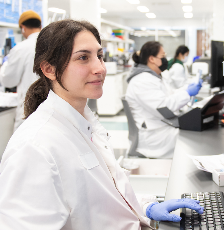 A Veracyte employee works on a computer in a Veracyte lab with her colleagues.