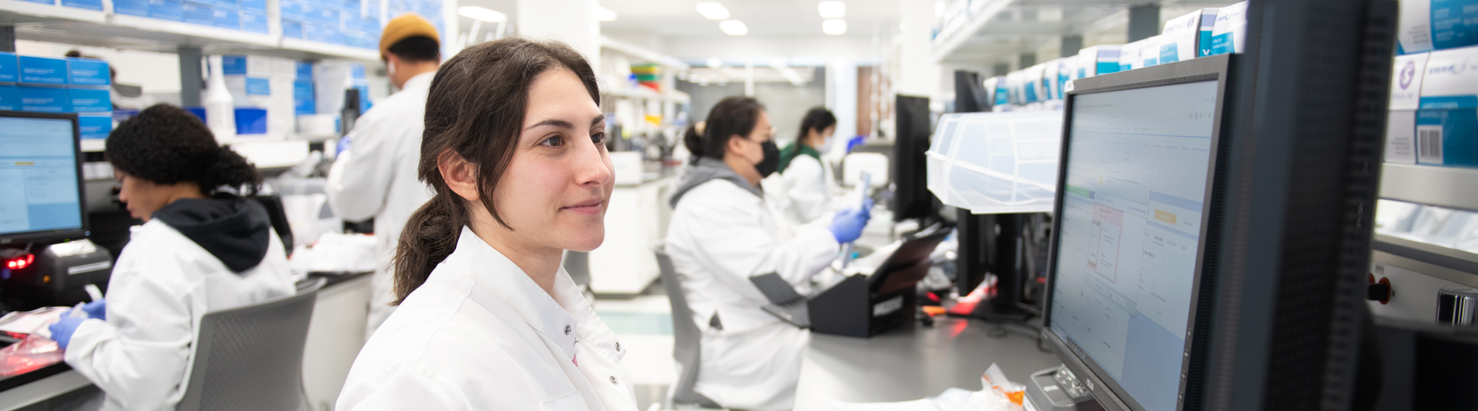 A Veracyte employee works on a computer in a Veracyte lab with her colleagues.