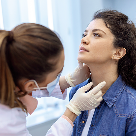 A woman looks up while a physician examines her throat.