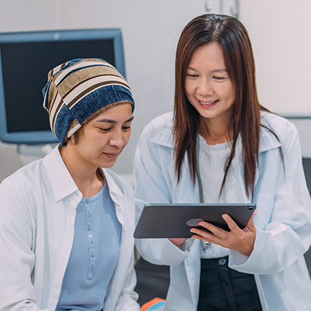 A smiling physician shows medical information to a patient.