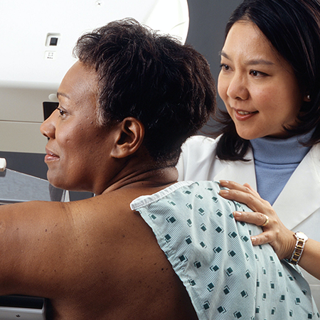 A woman receives a mammogram from a physician.