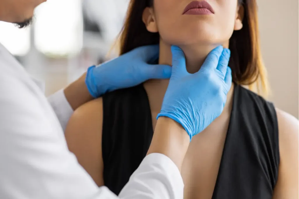 A health care provider wearing blue gloves examines a patient's neck for a medical assessment. The patient looks forward, creating a calm, clinical atmosphere.