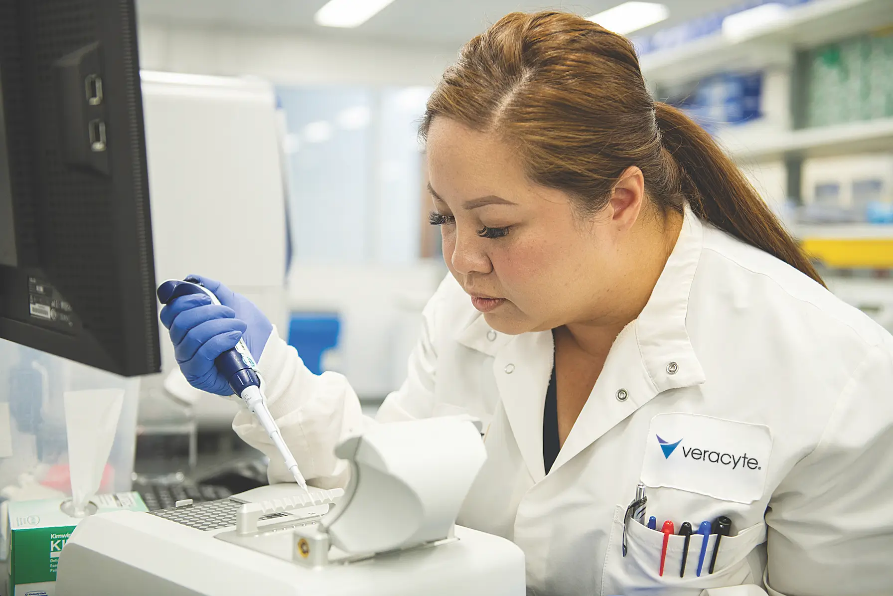 A scientist in a lab coat uses a pipette in a laboratory. The setting is organized and focused, highlighting concentration and precision.